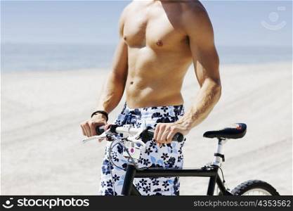 Mid section view of a man with a bicycle on the beach