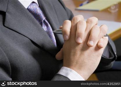 Mid section view of a man with his hands clasped
