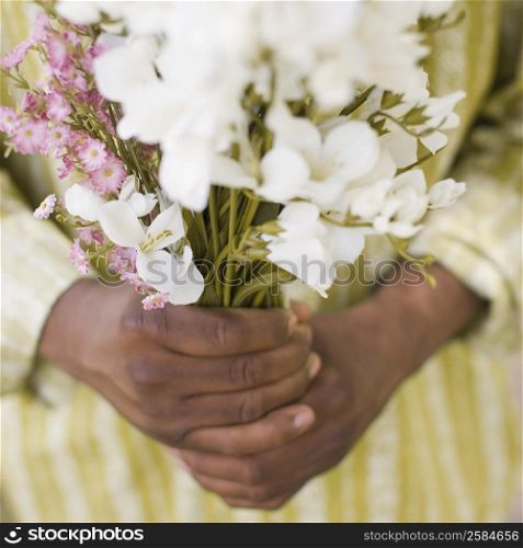 Mid section view of a mature man holding a bunch of flowers
