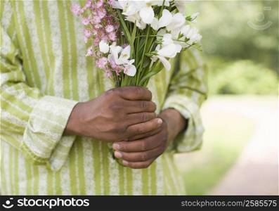 Mid section view of a mature man holding a bunch of flowers