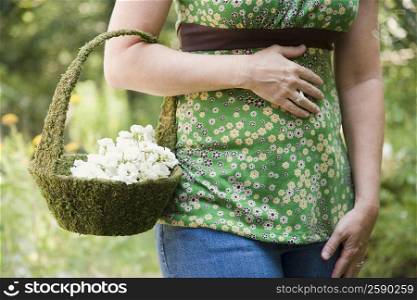 Mid section view of a mature woman holding a basket of flowers
