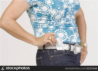 Mid section view of a mature woman putting a credit card into her pocket
