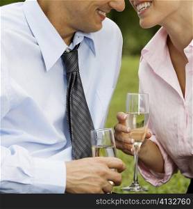 Mid section view of a mid adult man and a young woman holding champagne flutes