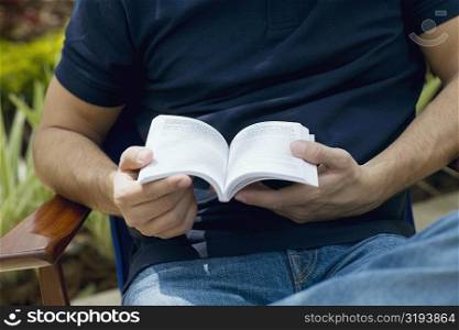 Mid section view of a mid adult man holding a book