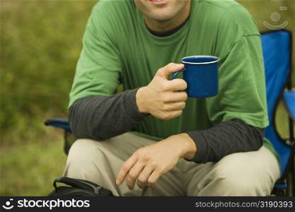 Mid section view of a mid adult man holding a coffee cup