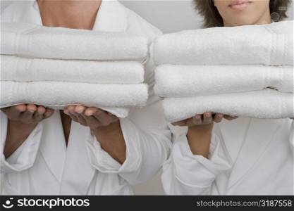 Mid section view of a mid adult man with a young woman holding stacks of folded towels