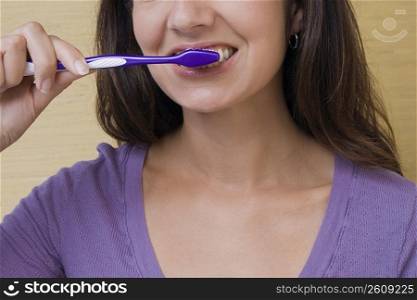 Mid section view of a mid adult woman brushing her teeth