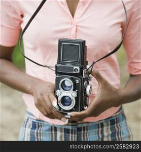 Mid section view of a mid adult woman holding a camera