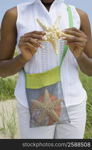 Mid section view of a mid adult woman holding a starfish