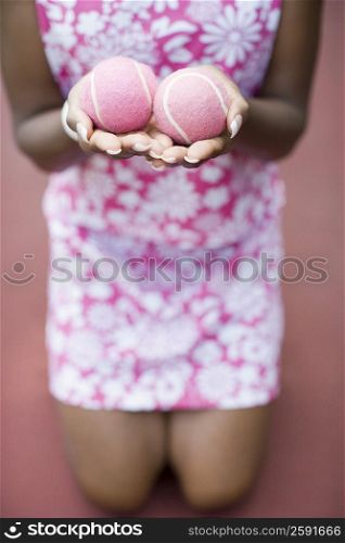 Mid section view of a mid adult woman holding tennis balls