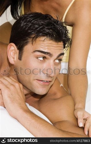 Mid section view of a mid adult woman massaging a mid adult man&acute;s shoulders on the bed
