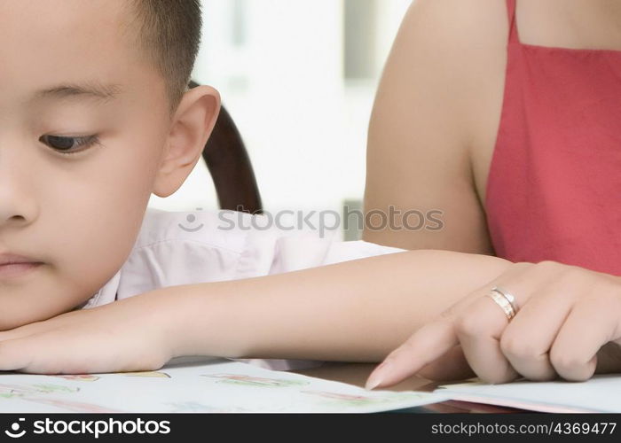 Mid section view of a mid adult woman teaching her son