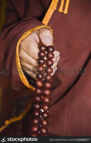 Mid section view of a monk&acute;s hand holding prayer beads, Da Zhao Temple, Hohhot, Inner Mongolia, China