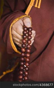Mid section view of a monk&acute;s hand holding prayer beads, Da Zhao Temple, Hohhot, Inner Mongolia, China