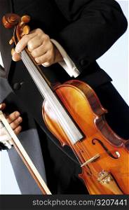 Mid section view of a musician holding a violin