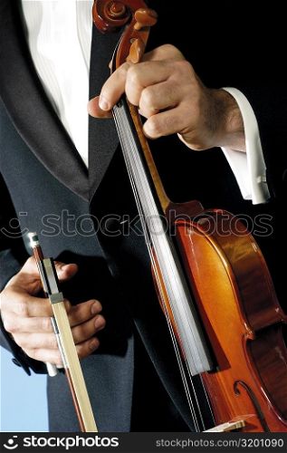 Mid section view of a musician holding a violin and a bow