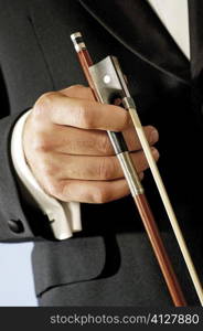 Mid section view of a musician holding the bow of a violin