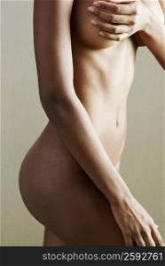 Mid section view of a naked woman covering her breast