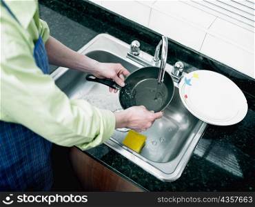 Mid section view of a person&acute;s hand washing a pan in the kitchen
