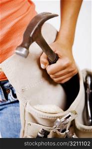 Mid section view of a person holding a hammer in a tool belt