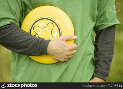 Mid section view of a person holding a plastic disc