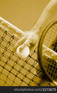 Mid section view of a person holding a tennis racket and tennis balls