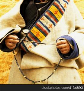 Mid section view of a person holding prayer beads, Lhasa, Tibet, China