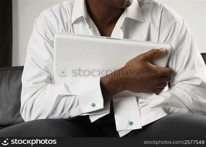 Mid section view of a person hugging a laptop