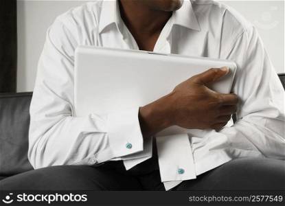 Mid section view of a person hugging a laptop