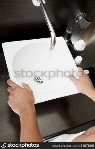 Mid section view of a person standing in front of a bathroom sink