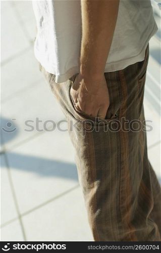 Mid section view of a person standing with his hands in his pockets