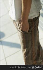 Mid section view of a person standing with his hands in his pockets