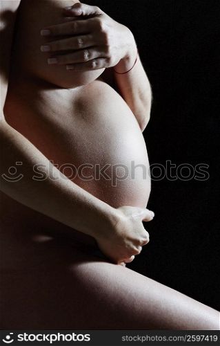Mid section view of a pregnant woman holding her abdomen
