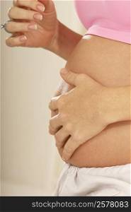 Mid section view of a pregnant woman touching her abdomen