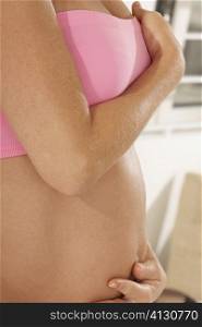 Mid section view of a pregnant woman touching her abdomen
