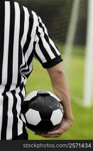 Mid section view of a referee carrying a soccer ball
