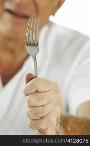 Mid section view of a senior man holding a fork