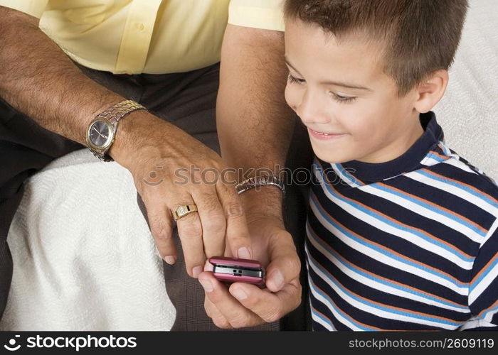 Mid section view of a senior man showing a mobile phone to his grandson