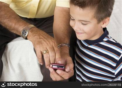 Mid section view of a senior man showing a mobile phone to his grandson