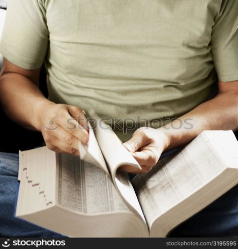 Mid section view of a senior man turning pages of a book