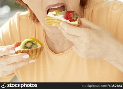 Mid section view of a senior woman eating a strawberry tart