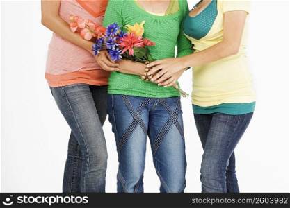 Mid section view of a senior woman standing with her two daughters and holding flowers