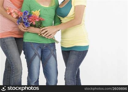 Mid section view of a senior woman standing with her two daughters and holding flowers