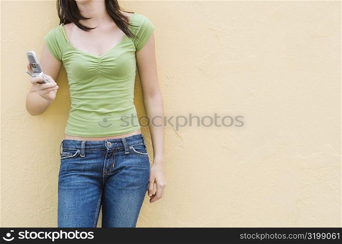 Mid section view of a teenage girl holding a mobile phone
