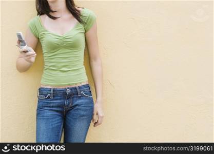 Mid section view of a teenage girl holding a mobile phone