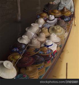 Mid section view of a vendor selling hats in a boat at a floating market, Bangkok, Thailand