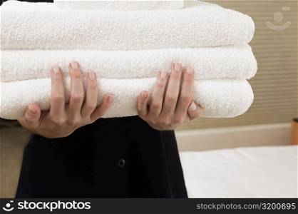 Mid section view of a waitress holding a stack of towels