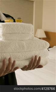 Mid section view of a waitress holding a stack of towels