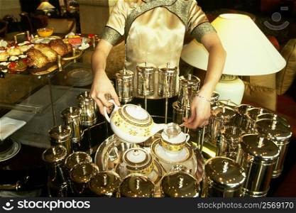 Mid section view of a waitress pouring tea in tea cups, Pudong Shangri-La, Shanghai, China