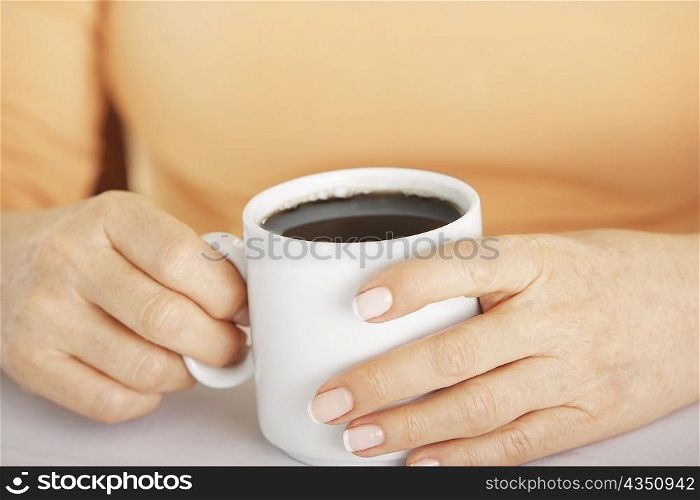 Mid section view of a woman&acute;s hand holding a cup of coffee